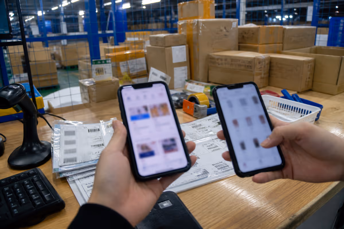 Futian warehouse packing desk with two phones and carton stacks suggesting multi-channel APAC commerce.